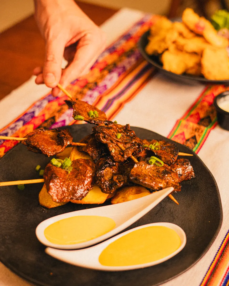 Anticuchos de coração bovino com batatas douradas e molho